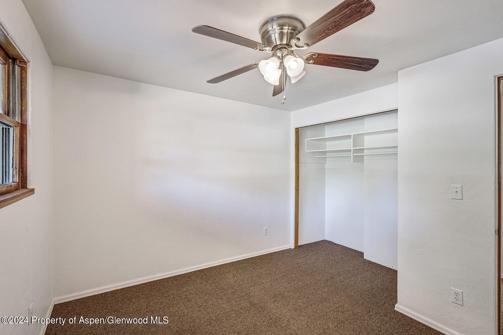 902 Randolph Avenue Rifle, CO 81650 - Photo 8 of 18 an empty room with a chandelier fan and a wooden floor
