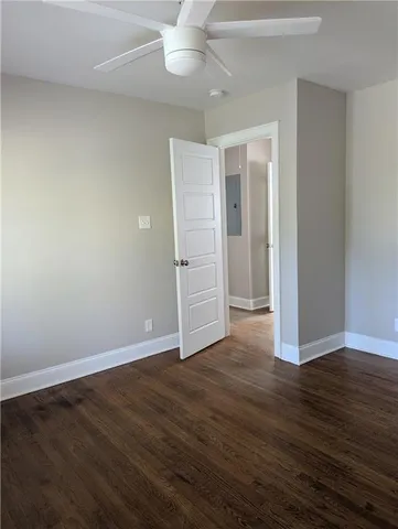 an empty room with wooden floor closet fan and windows