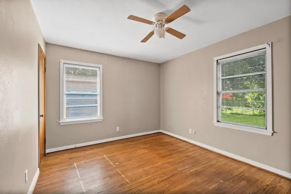 an empty room with wooden floor and windows