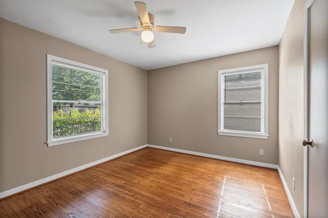 a view of an empty room with a window and wooden floor