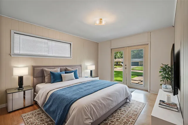 a bedroom with a bed a flat tv screen and a potted plant