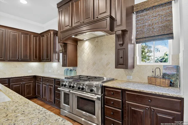 a kitchen with granite countertop stainless steel appliances a stove sink and cabinets