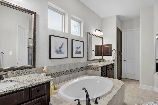 a bathroom with a granite countertop tub sink and mirror