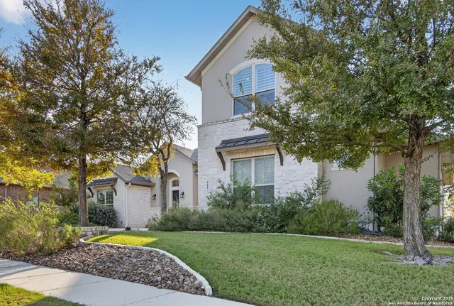 a front view of a house with a yard and tree s