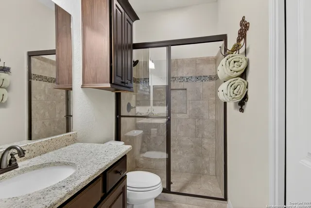 a bathroom with a granite countertop sink toilet and shower