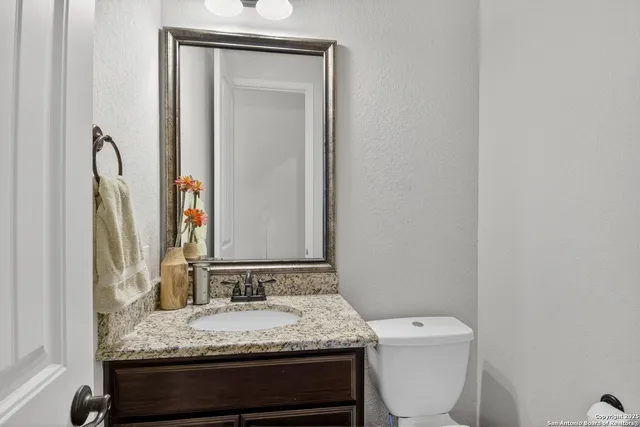 a bathroom with a granite countertop sink toilet and mirror