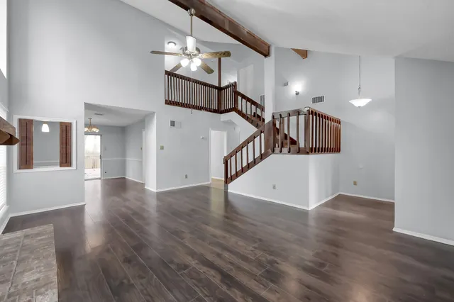 an empty room with wooden floor and staircase