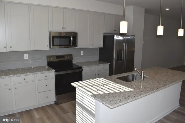 a kitchen with stainless steel appliances granite countertop a sink a stove and a refrigerator