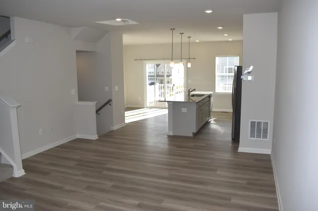 a view of kitchen with stainless steel appliances granite countertop refrigerator sink and wooden floor