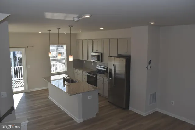 a kitchen with kitchen island a counter top space a sink stainless steel appliances and cabinets