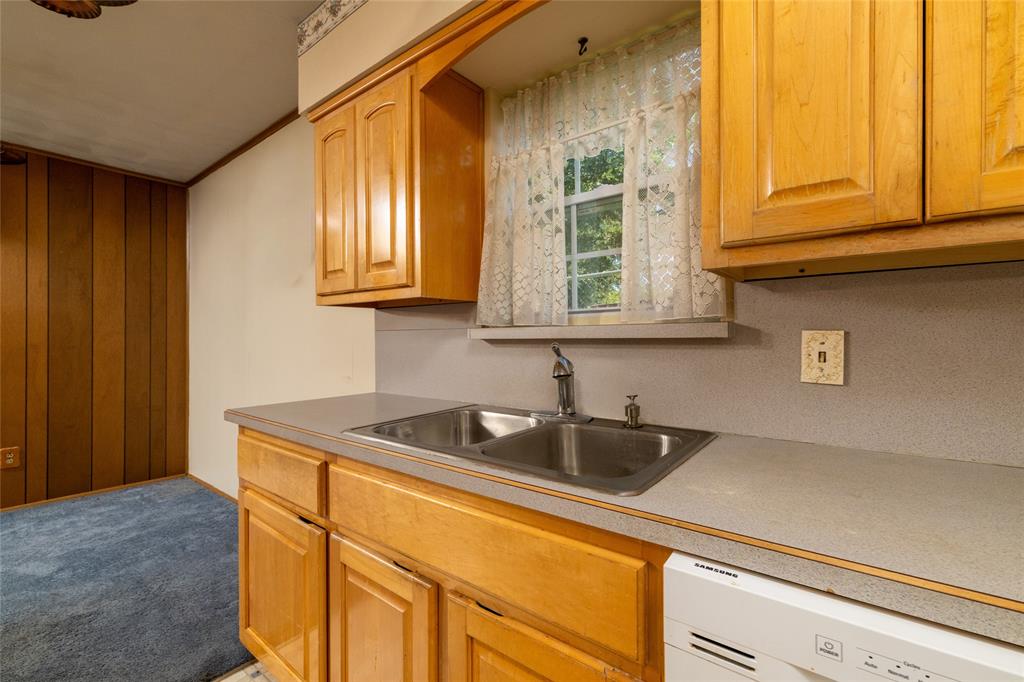 3605 Pleasant Run Road Irving, TX 75062 - Photo 23 of 32 Galley kitchen featuring warm wood cabinetry, stainless steel double-basin sink with chrome faucet, laminate countertops, and white electric range