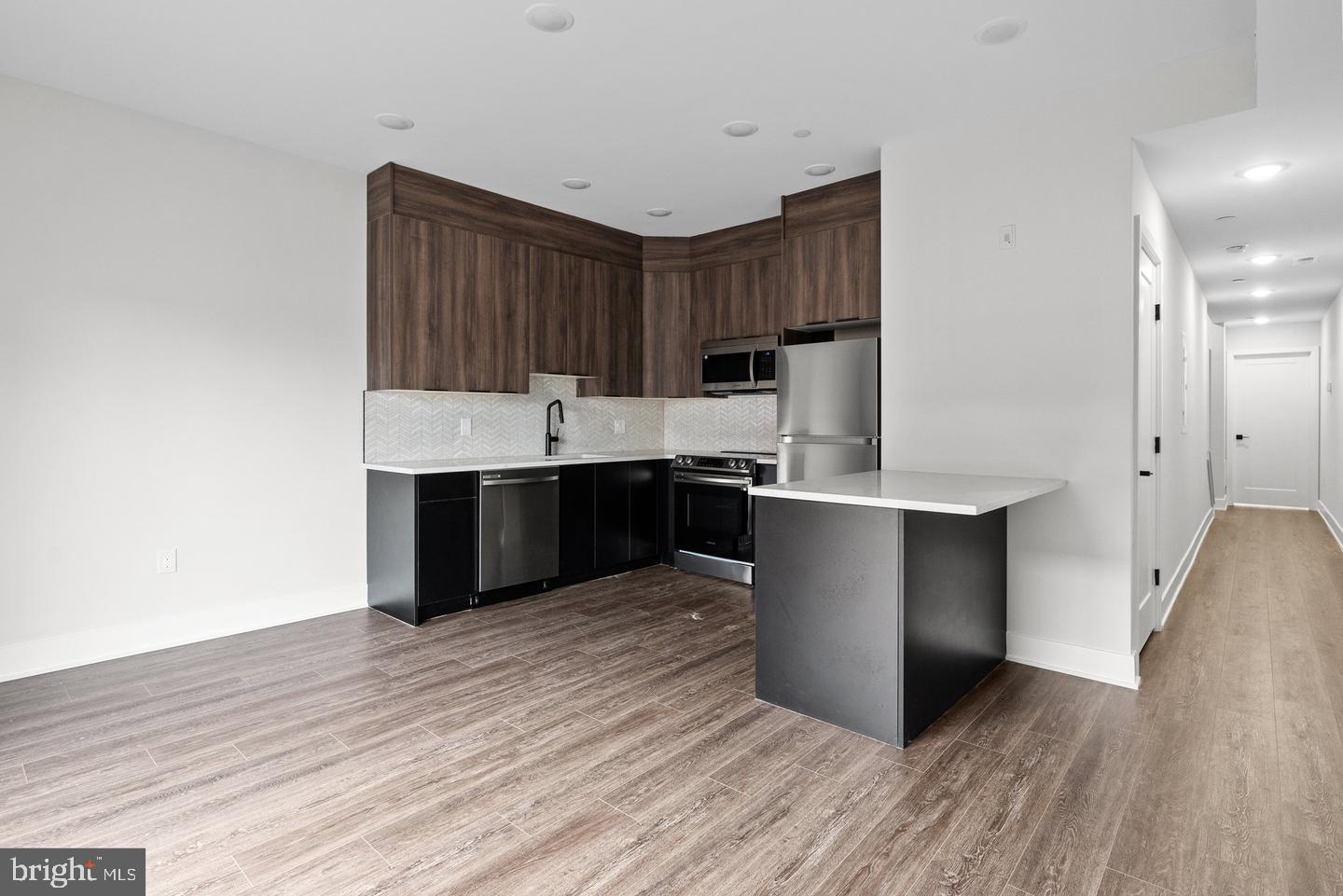 2146 North Front Street Philadelphia, PA 19122 - Photo 27 of 39 a room with kitchen island stainless steel appliances a sink cabinets and wooden floor