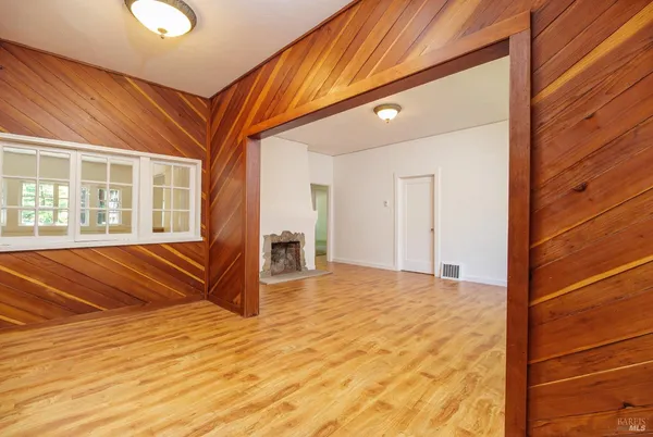 a view of an empty room with wooden floor and a fireplace