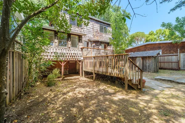 a view of a backyard with wooden fence and a large tree