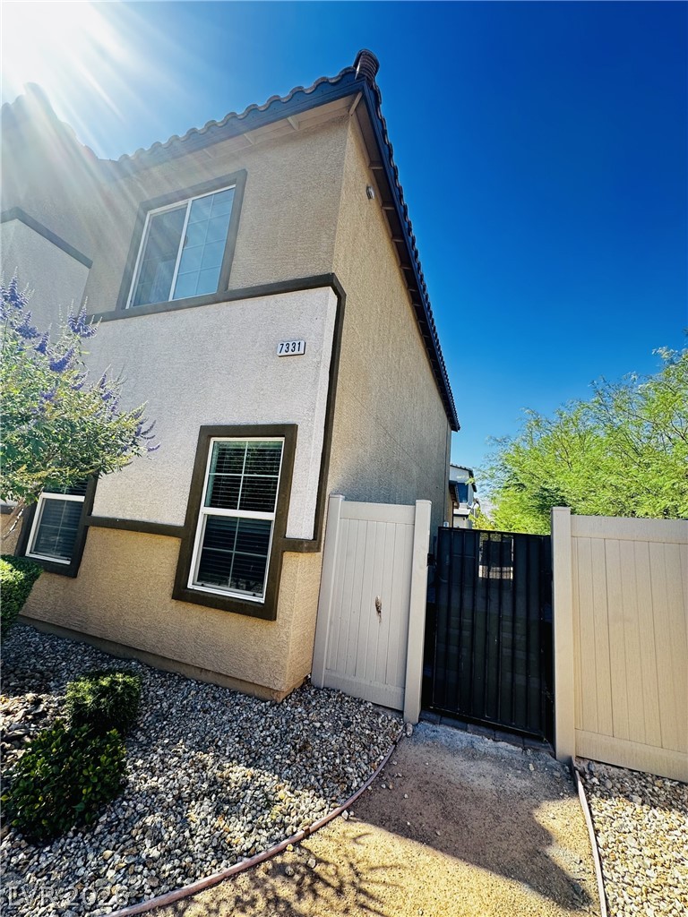 7331 Sunray Point Street North Las Vegas, NV 89084 - Photo 15 of 20 A desert-friendly landscape accents the stucco exterior of this multi-level residence, framed by a vibrant blue sky.