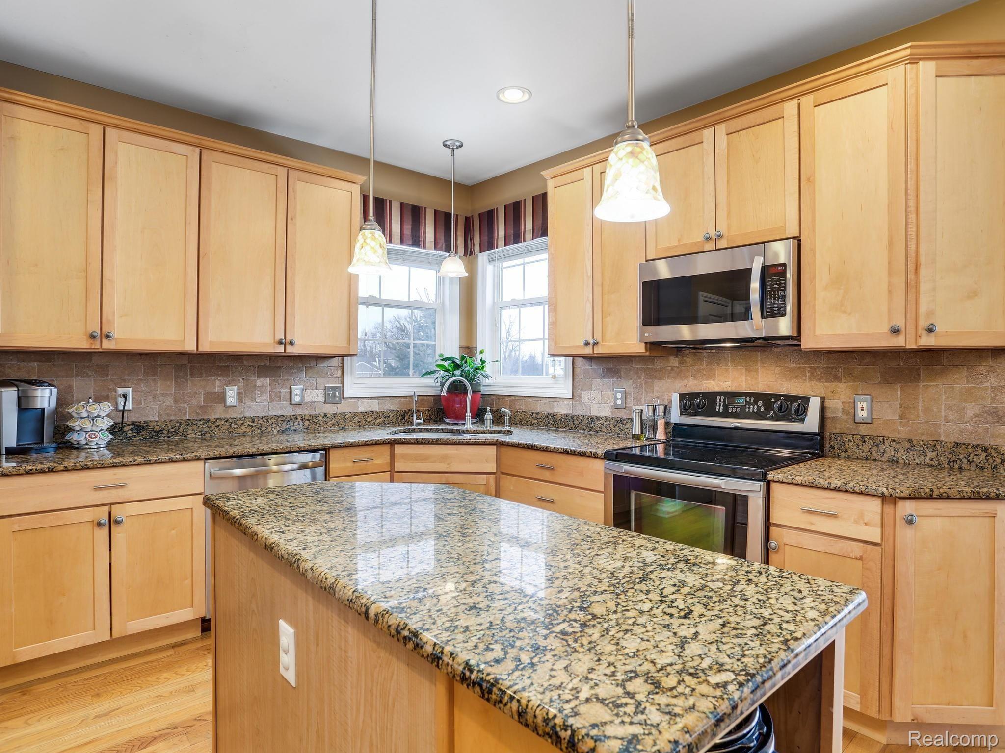 1067 Marsh Ridge Brighton, MI 48114 - Photo 10 of 39 Extensive granite counters in the beautiful light and bright kitchen. Upgraded lighting over the island kitchen cabinet.