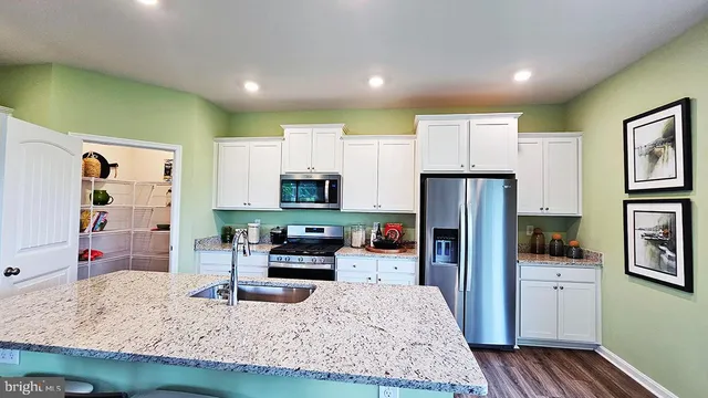 a kitchen with stainless steel appliances kitchen island granite countertop a refrigerator stove oven and sink