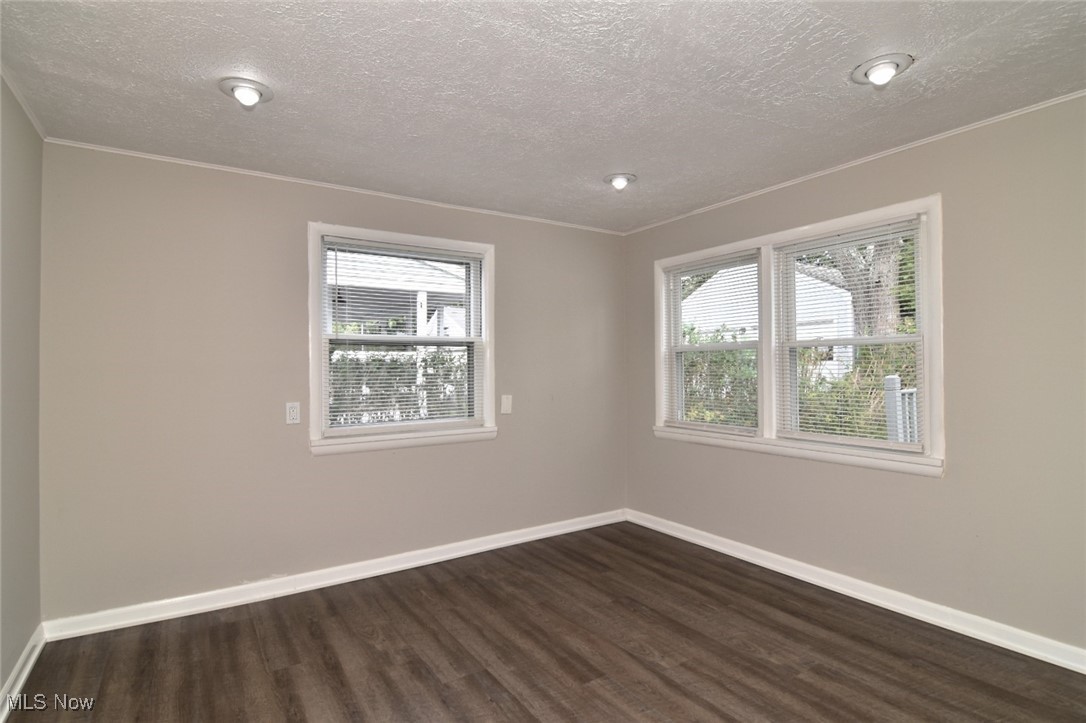 1443 Churchill Road Lyndhurst, OH 44124 - Photo 14 of 39 Unfurnished room with dark wood-style flooring, plenty of natural light, ornamental molding, and a textured ceiling