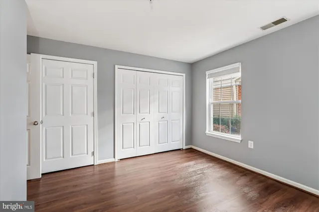 an empty room with wooden floor and windows with curtains