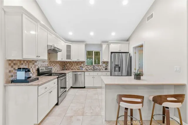 a kitchen with stainless steel appliances granite countertop a refrigerator and a stove top oven