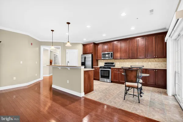 a kitchen with kitchen island granite countertop wooden floors wooden cabinets and appliances