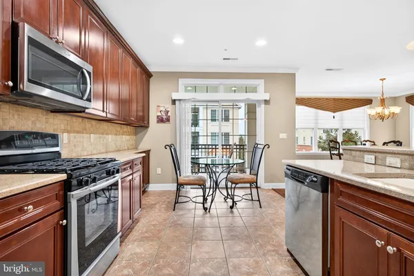 a kitchen with stainless steel appliances granite countertop a stove top oven a sink dishwasher a dining table and chairs with wooden floor