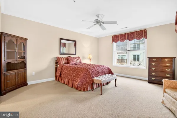 a spacious bedroom with a bed a dresser and a large window