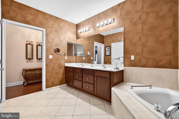 a spacious bathroom with a sink double vanity granite tub shower and a mirror