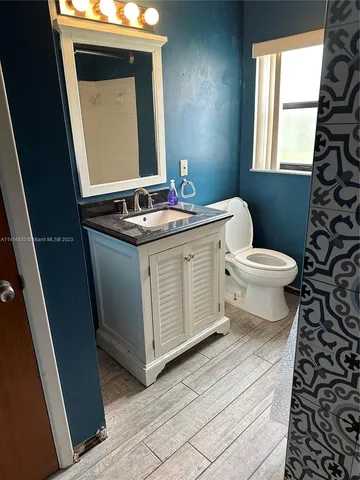a bathroom with a granite countertop toilet sink and mirror