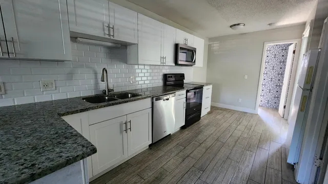 a kitchen with granite countertop a sink stove and cabinets