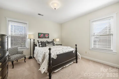 a bed sitting in a bedroom next to a window and a chair