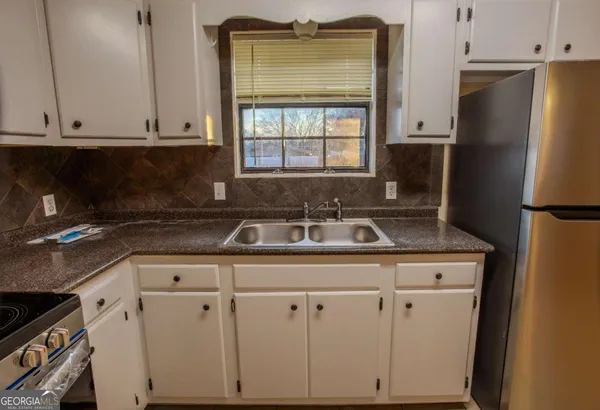 a kitchen with granite countertop white cabinets and refrigerator