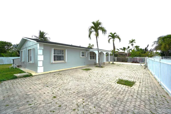 a backyard of a house with potted plants and palm trees