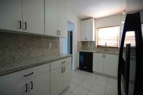 a kitchen with granite countertop a sink a stove and refrigerator