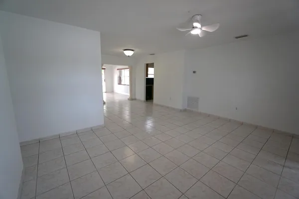 an empty room with chandelier fan and window