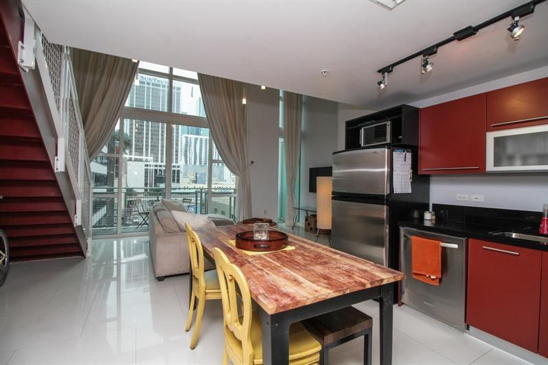 253 Northeast 2nd Street, Unit 421 Miami, FL 33132 - Photo 7 of 39 a kitchen with stainless steel appliances granite countertop a table chairs a refrigerator and a sink