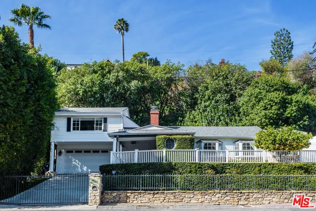 a front view of a house with a yard and potted plants