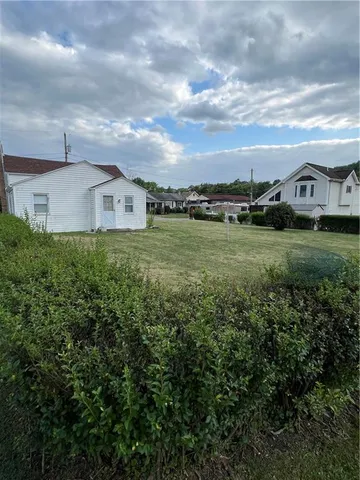 a view of a big house with a big yard and large trees