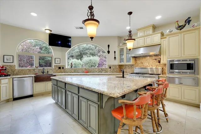 a kitchen with stainless steel appliances granite countertop a sink a stove and a wooden cabinets