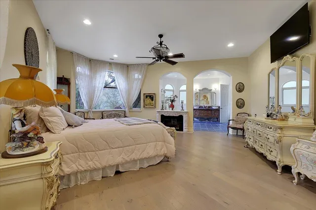 a spacious bedroom with a bed a chandelier and dresser