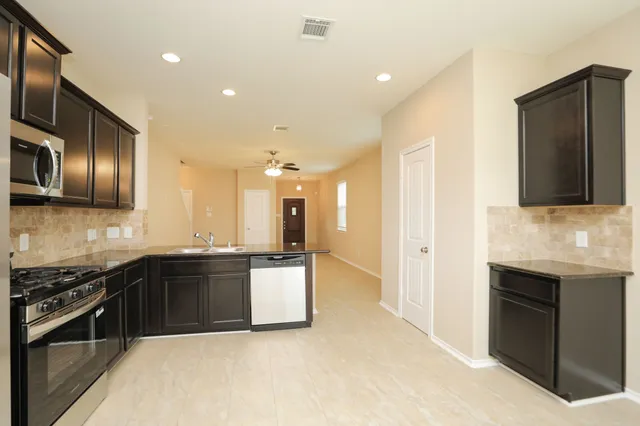 a large kitchen with stainless steel appliances granite countertop a stove top oven a sink and a granite counter top