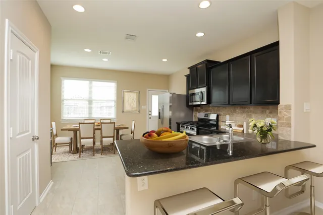 a kitchen with stainless steel appliances granite countertop a refrigerator a stove a sink and a microwave