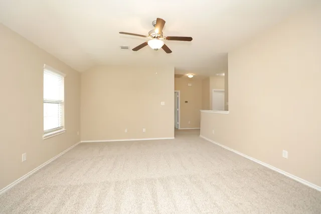 an empty room with a window and a fan