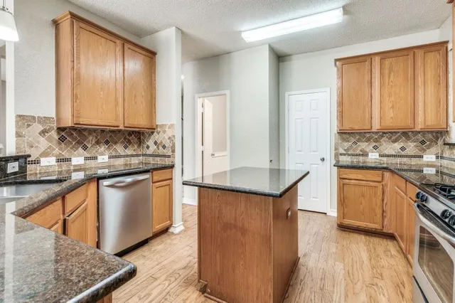 a kitchen with stainless steel appliances granite countertop wooden cabinets a sink and a stove