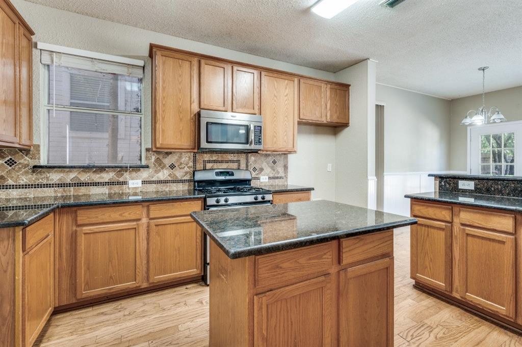 4933 Glenscape Trail Fort Worth, TX 76137 - Photo 7 of 12 a kitchen with stainless steel appliances granite countertop a sink stove microwave and refrigerator
