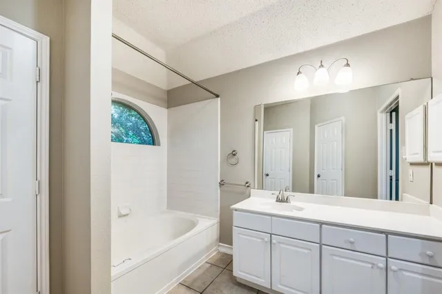 a bathroom with a tub a sink and mirror