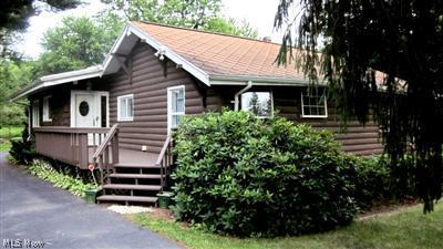 Enjoy country living in the city! This unique log cabin ranch features an attached 4 car heated tandem garage, circular driveway, city water and sewer and is nestled on a beautiful 1+ acre lot.    Built in 1938 with an add on in the 60's that included a kitchen, dining area and great room with hardwood floor and stone wall fireplace.