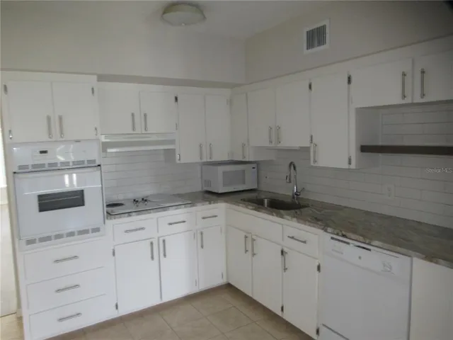 a kitchen with white cabinets and white appliances