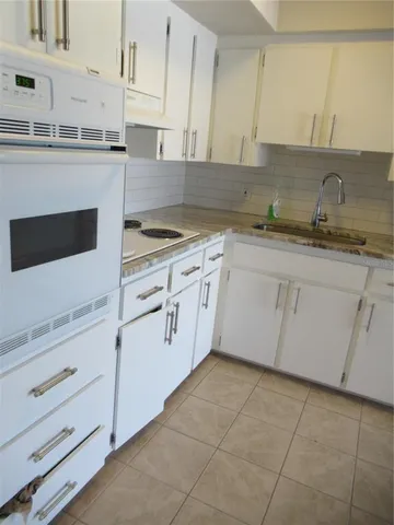 a kitchen with white cabinets and sink