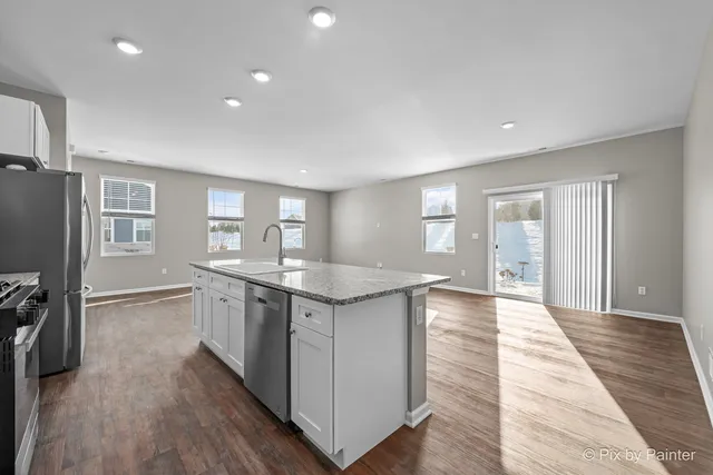 a large kitchen with stainless steel appliances granite countertop a lot of counter space and wooden floor